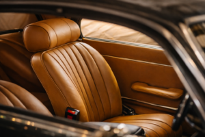 Close-up of a custom tan leather driver’s seat with pleated stitching inside a classic car interior